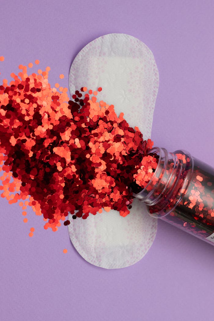 Artistic take on feminine hygiene featuring a sanitary pad and glitters on purple backdrop.