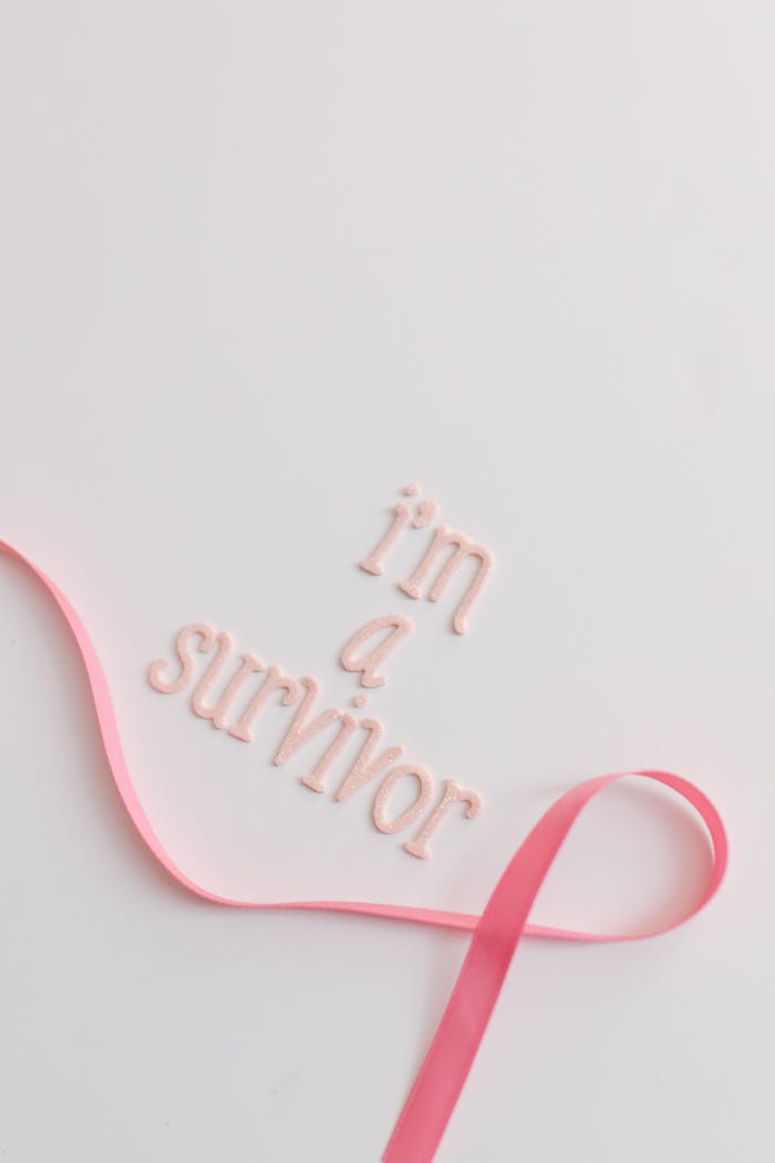 Empowering cancer survivor message with pink ribbon on white background for awareness.